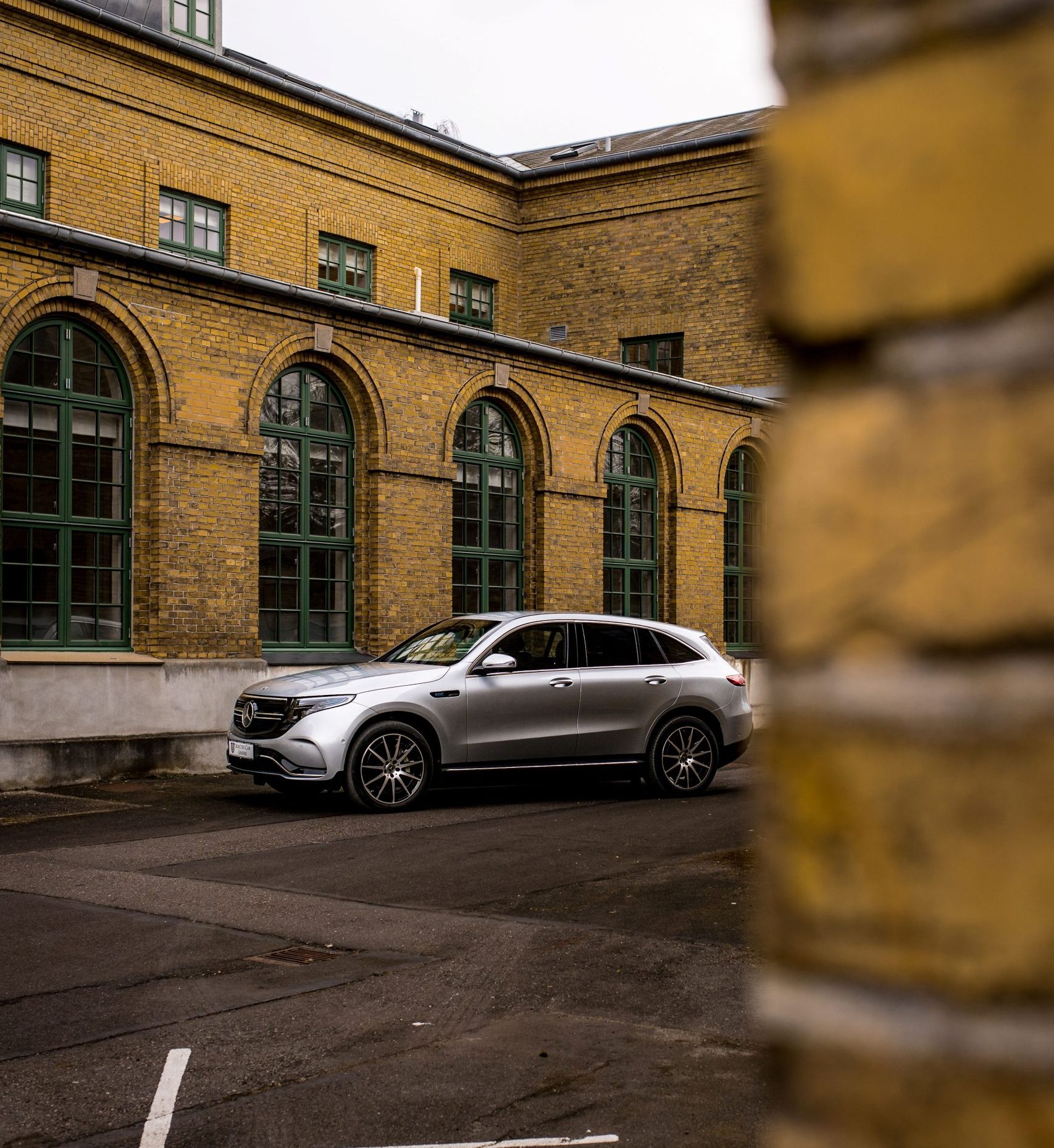 Sølvfarvet Mercedes-Benz EQC foran murstensbygning